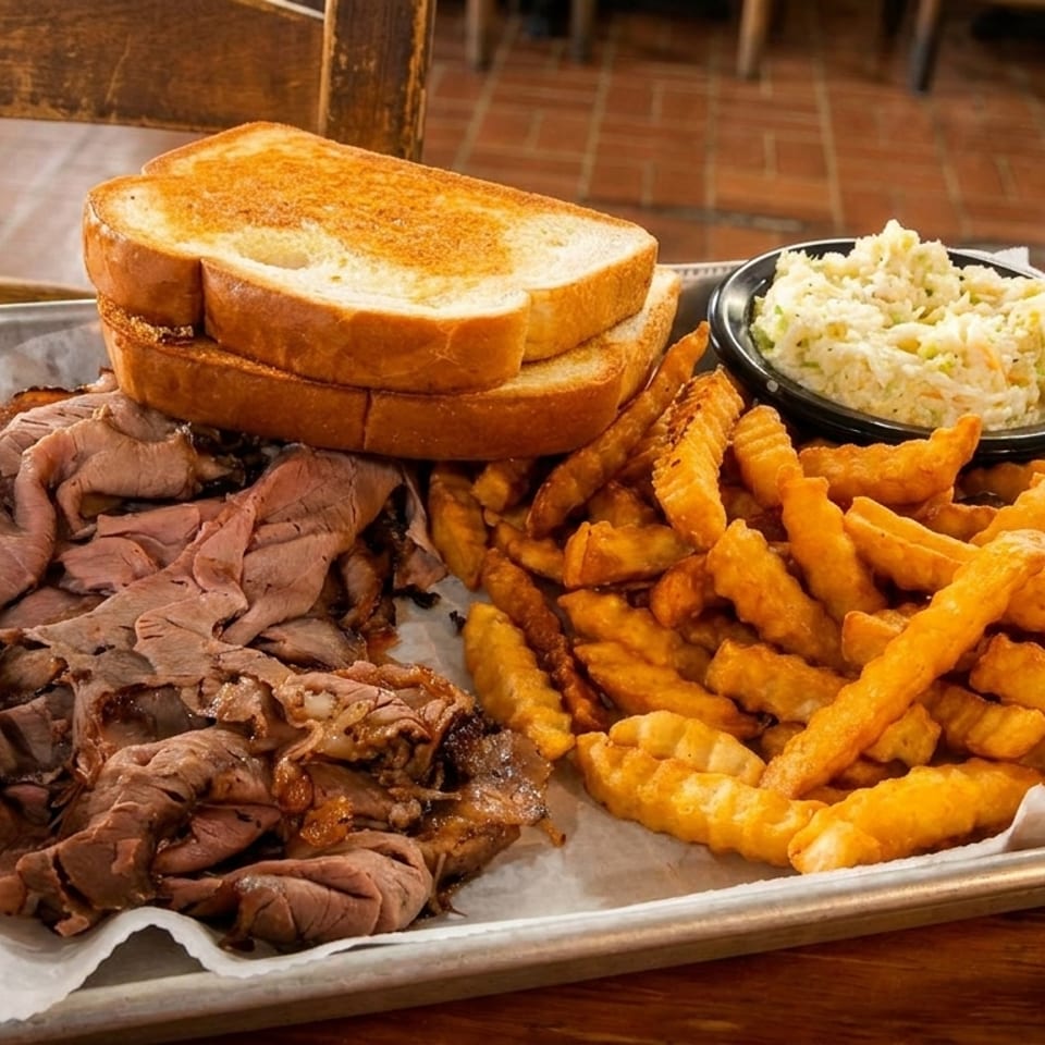 A metal tray with sliced roast beef, crinkle-cut fries, coleslaw, and toasted bread.